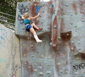 Isabel climbing a rock wall with a leg cast. 